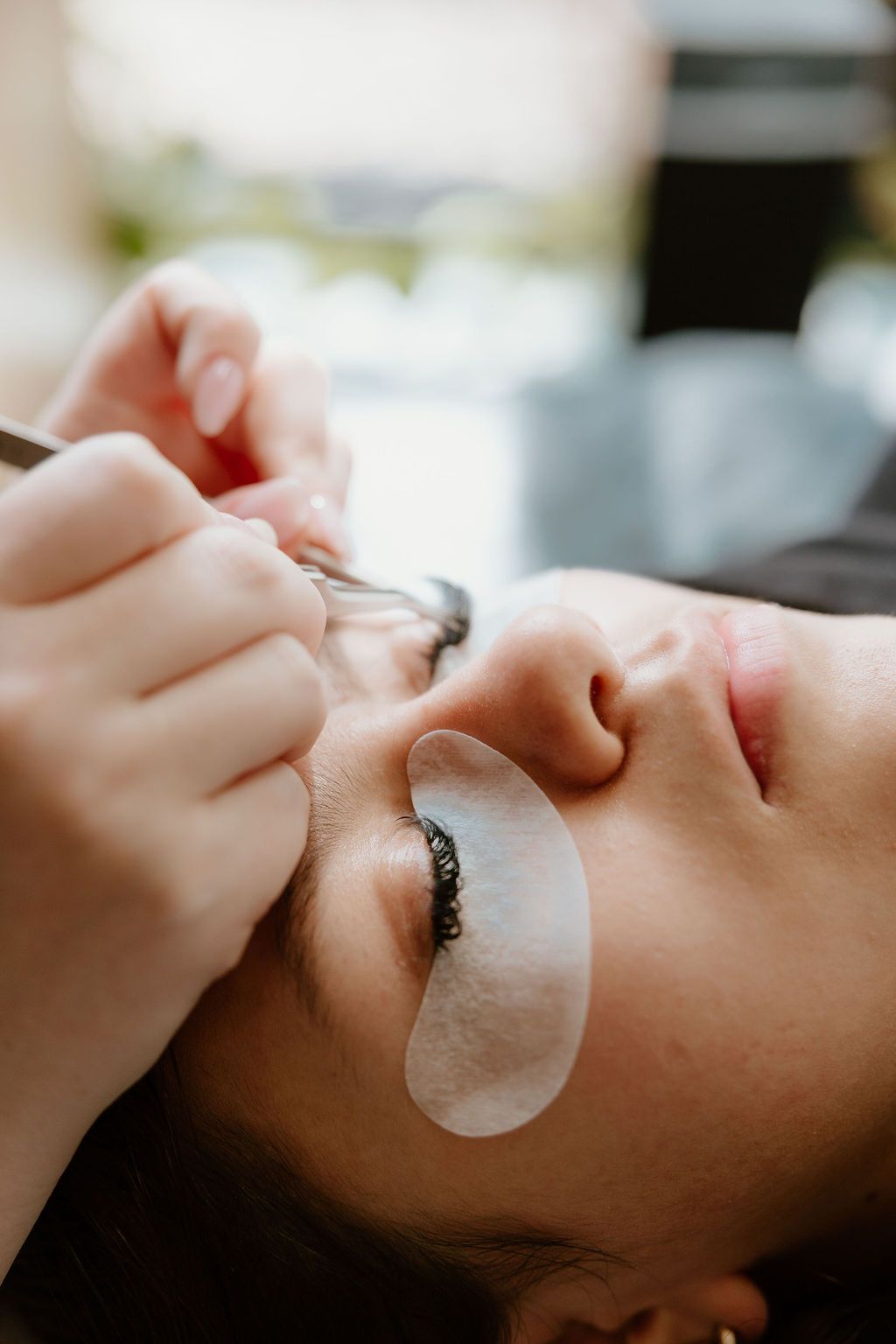 Side view of a client with an eye pad on while lashes are applied