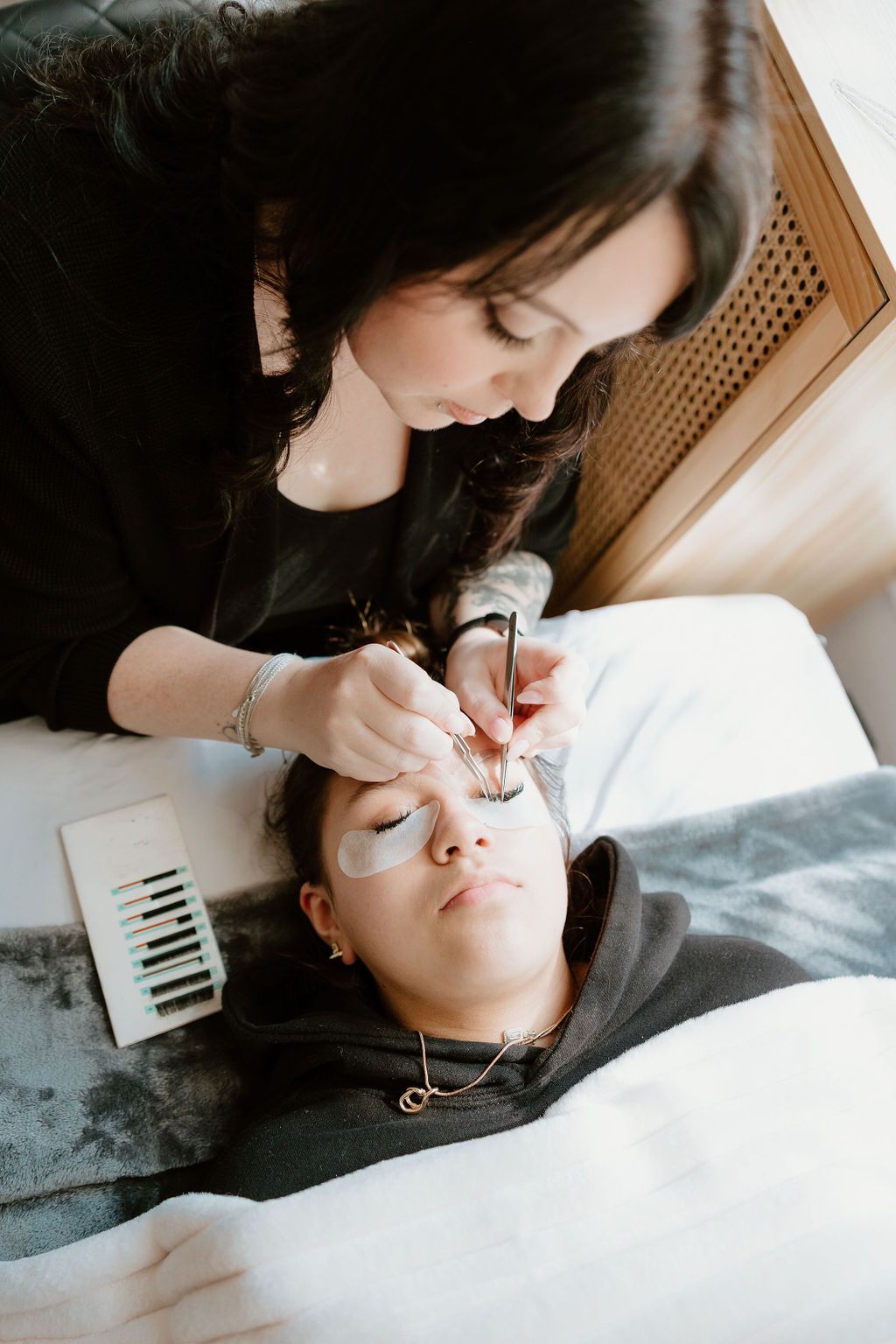 Lash artist leaning over a client, applying extensions