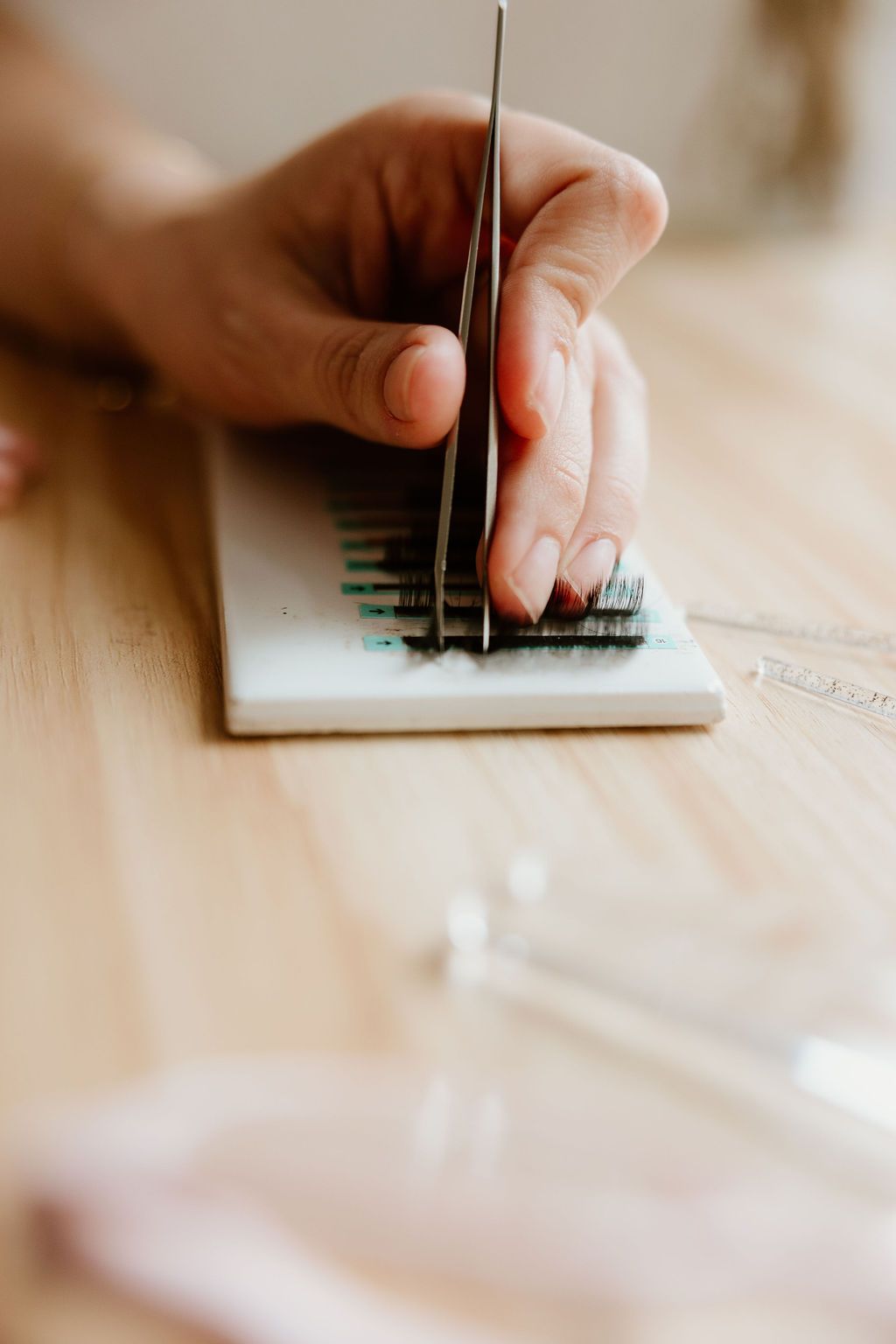 Tweezers lifting lashes from a strip of extensions