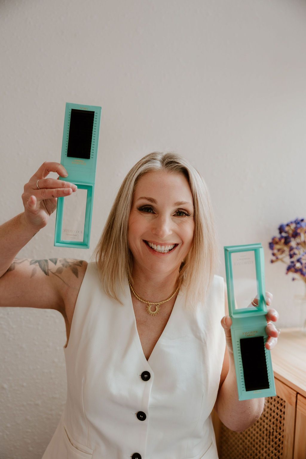 Lash artist smiling and holding up two mint green lash trays