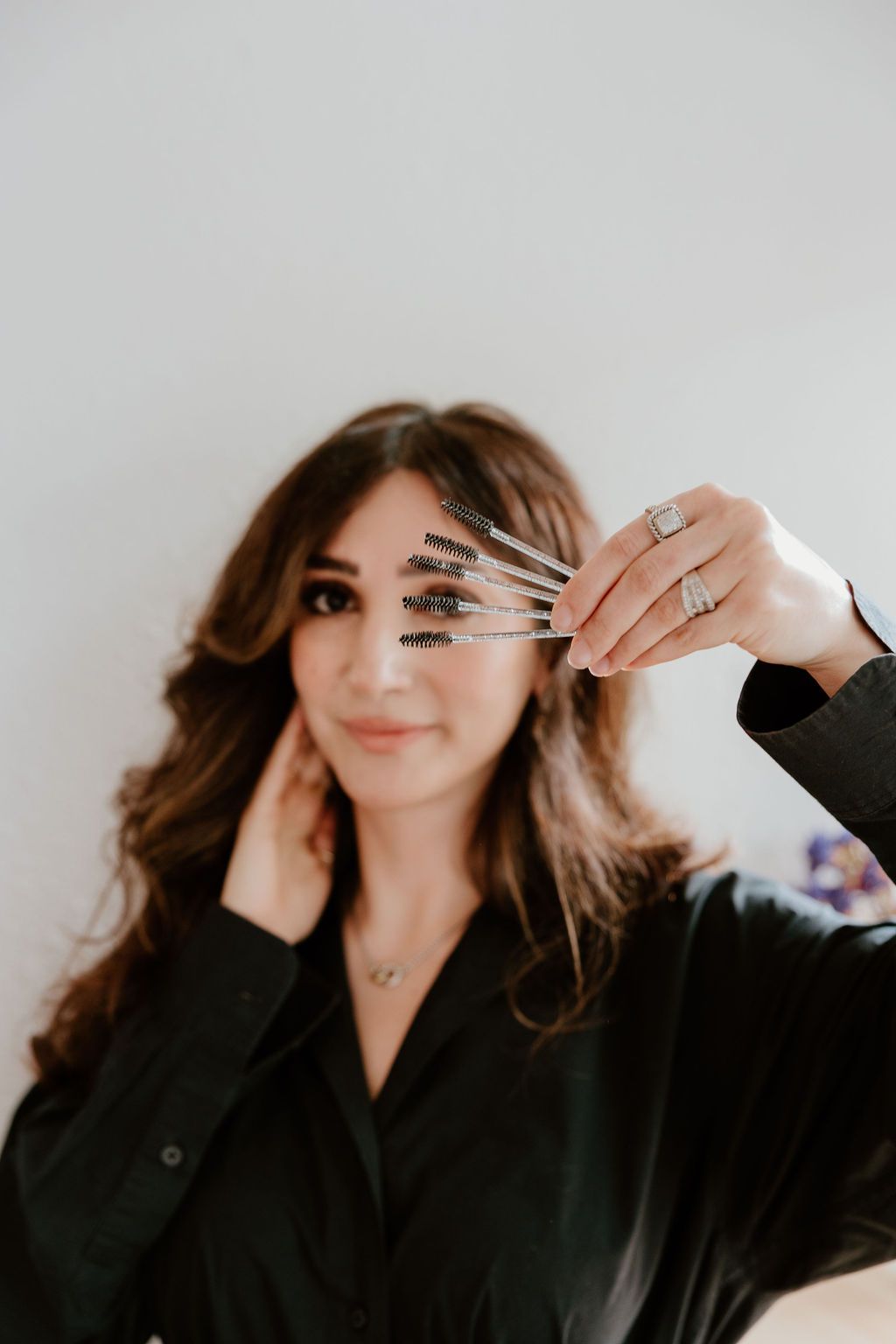 Lash artist holding a strip of lash extensions up to her eyes