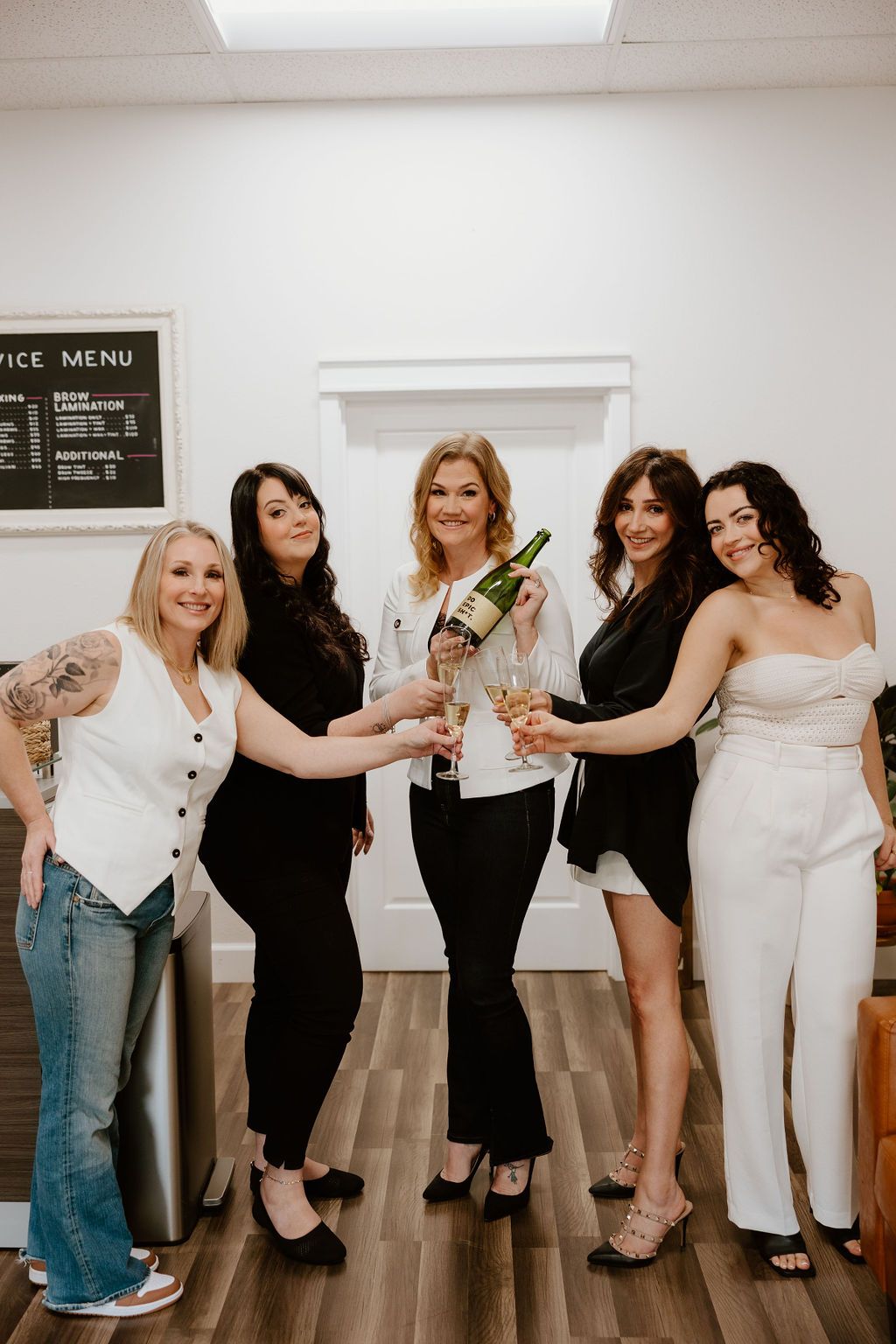 Five members of the Lash Candy team toasting with champagne in the salon